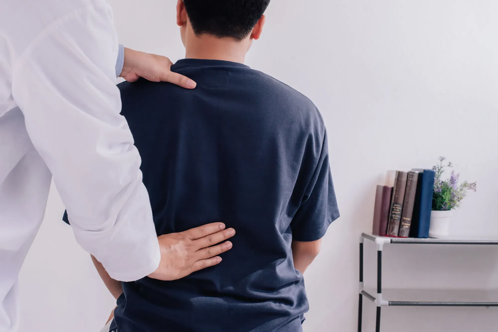 A medical professional assessing a man’s back for injuries