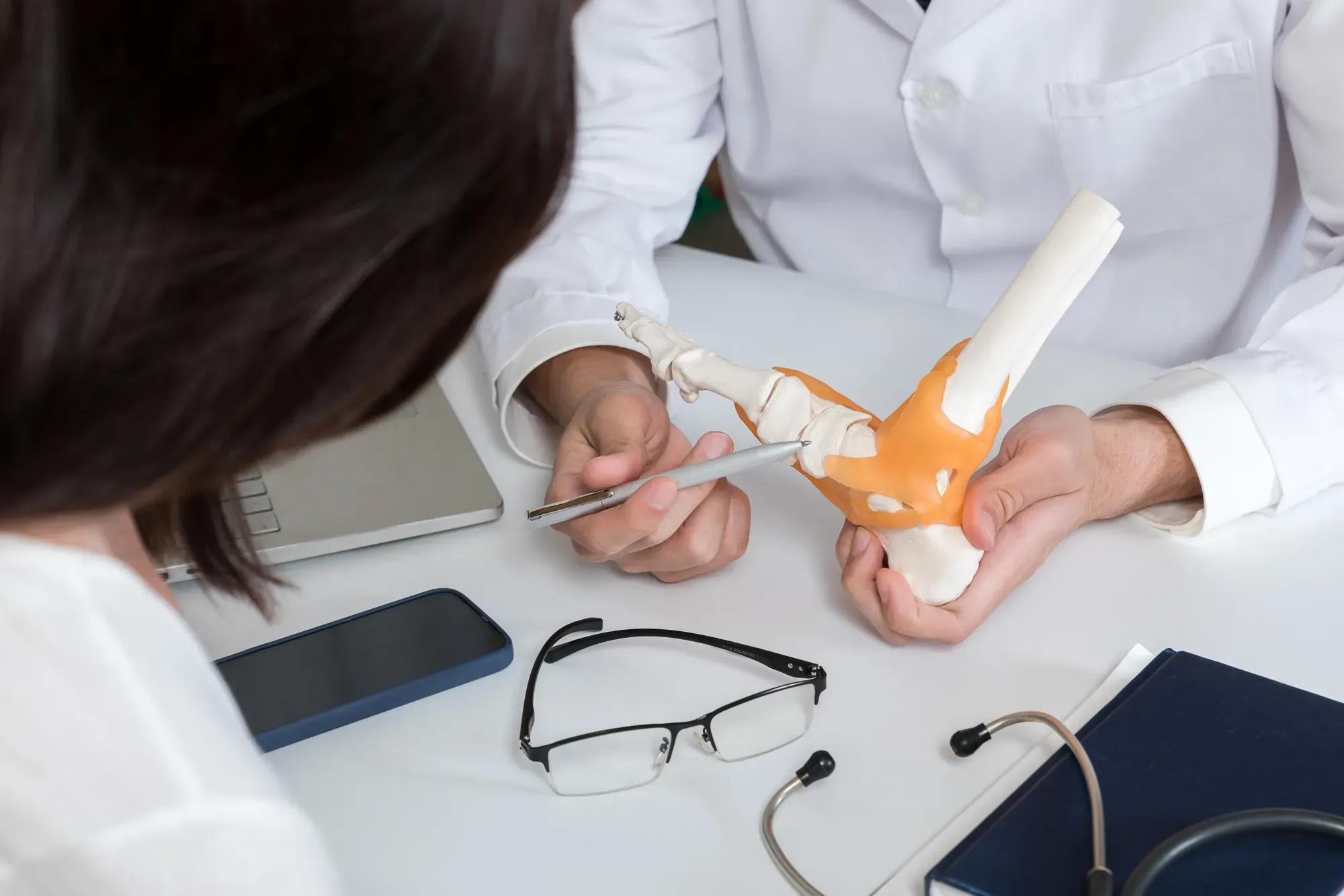 A specialist referring to a model of the human foot in a consultation for chronic instability.