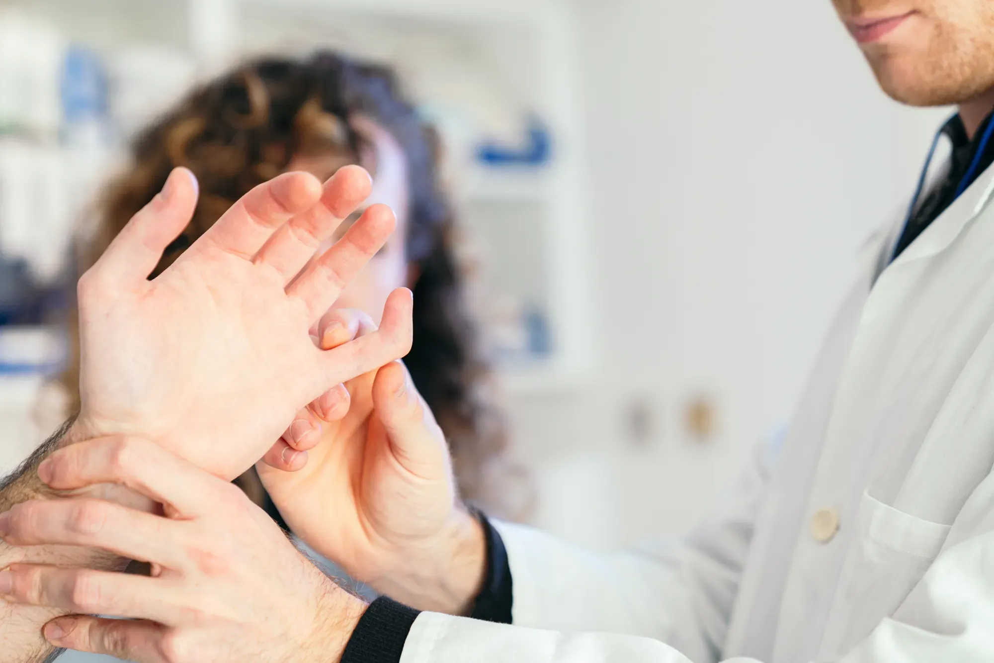 Specialist examining patient’s hand during a consultation for nerve compression.