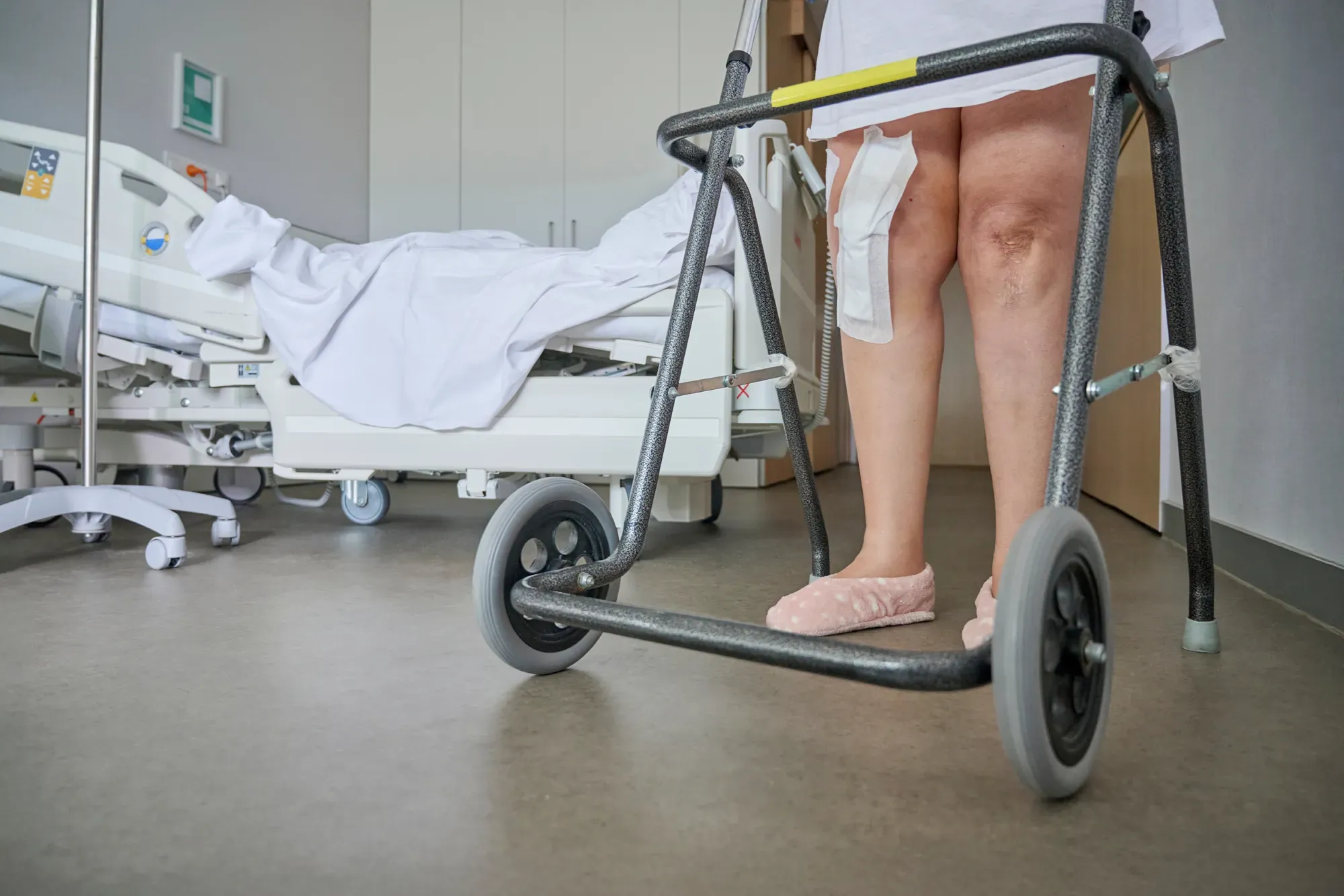 A patient taking her first steps after a knee replacement surgery.