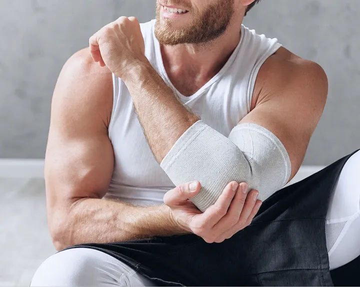 Person wearing a compression bandage on the elbow to support recovery from an elbow injury.
