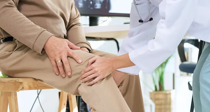 Orthopaedic specialist examining a patient's knee during a consultation in Singapore.