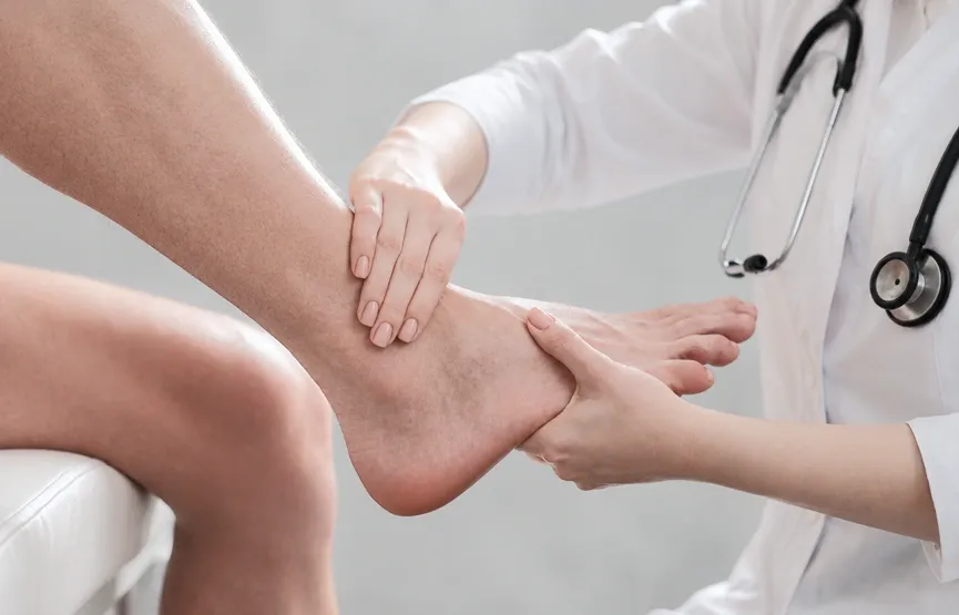 A medical professional in a white coat manually checking the ankle mobility and foot joint alignment of a patient.