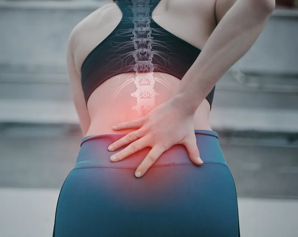 A woman in athletic wear holding her painful lower back, with a digital graphic overlay showing her spine and a red glow indicating injury.
